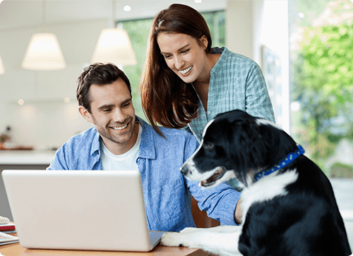 man looking at a laptop with a dog and a woman next to him